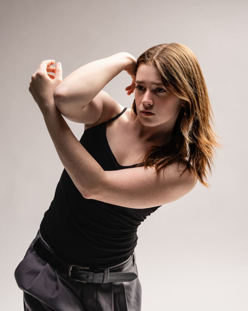 Contemporary dancer in soft lighting crossing arm.
