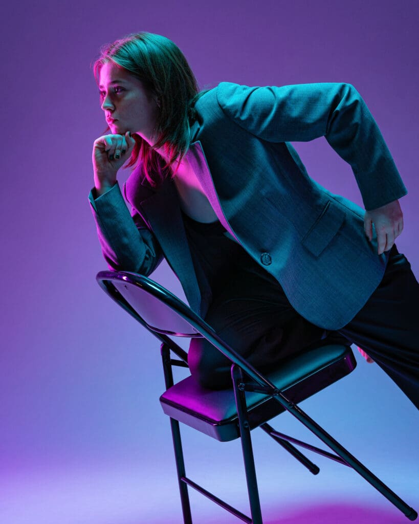 Contemporary dancer leaning on a chair looking focused.
