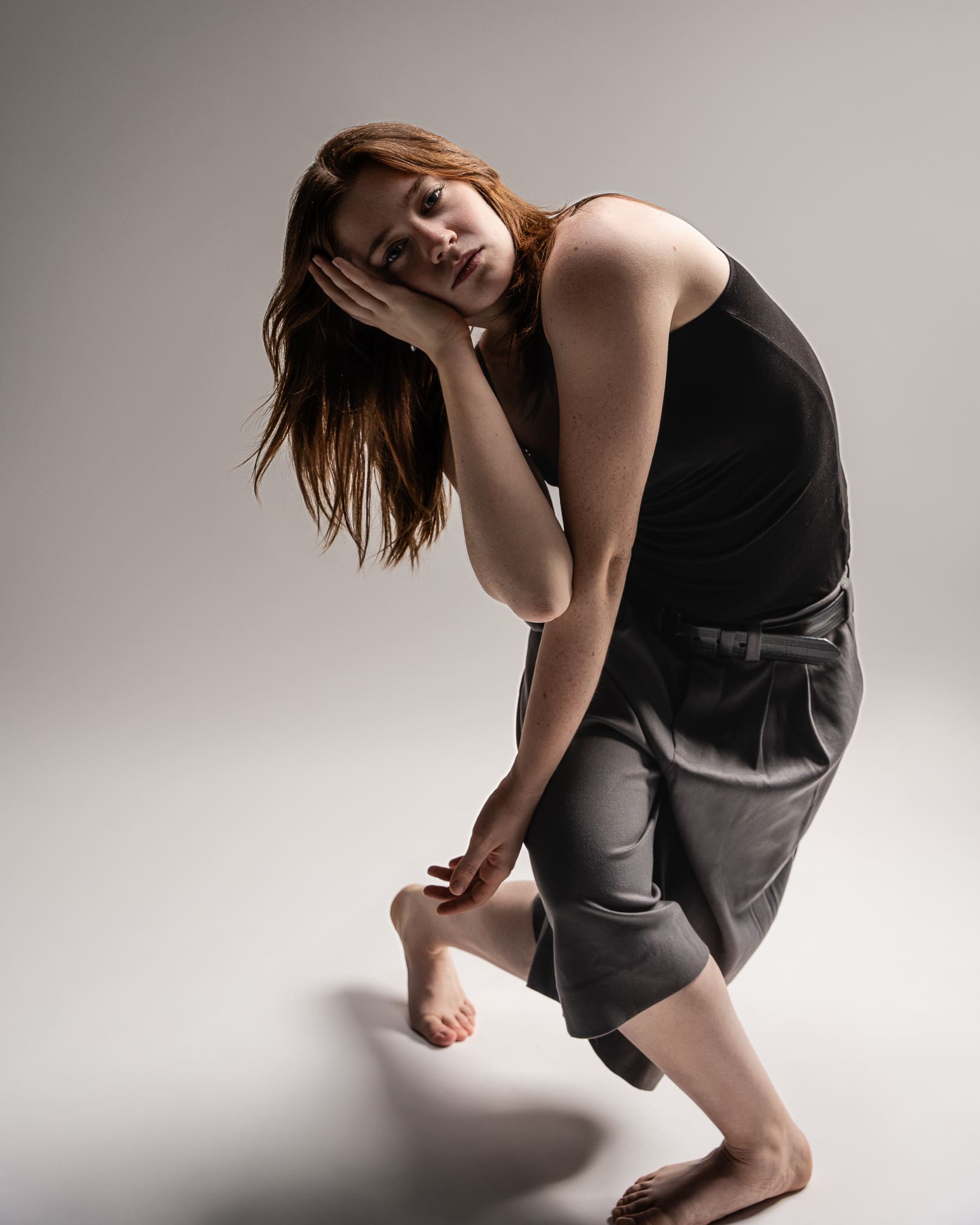 Dancer resting her head on her hand in a soft, tilted pose during a contemporary dance photoshoot in San Antonio