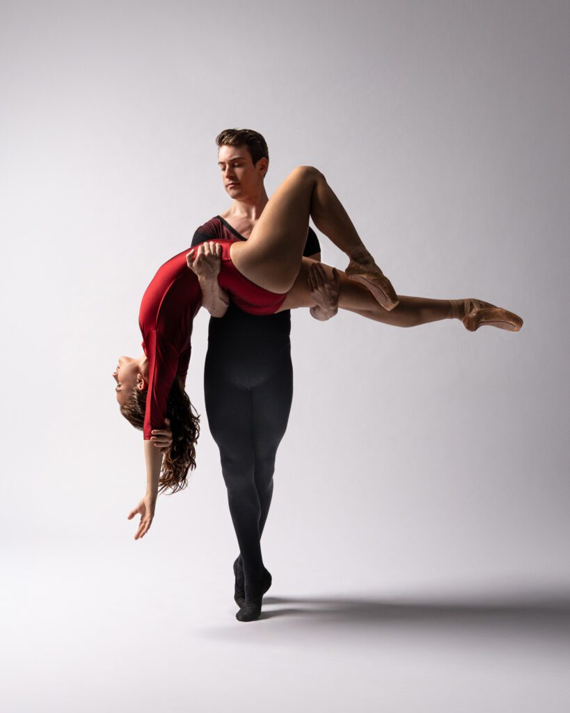Male dancer lifts female dancer in an passe lift during a San Antonio dance session, both posed in performance technique