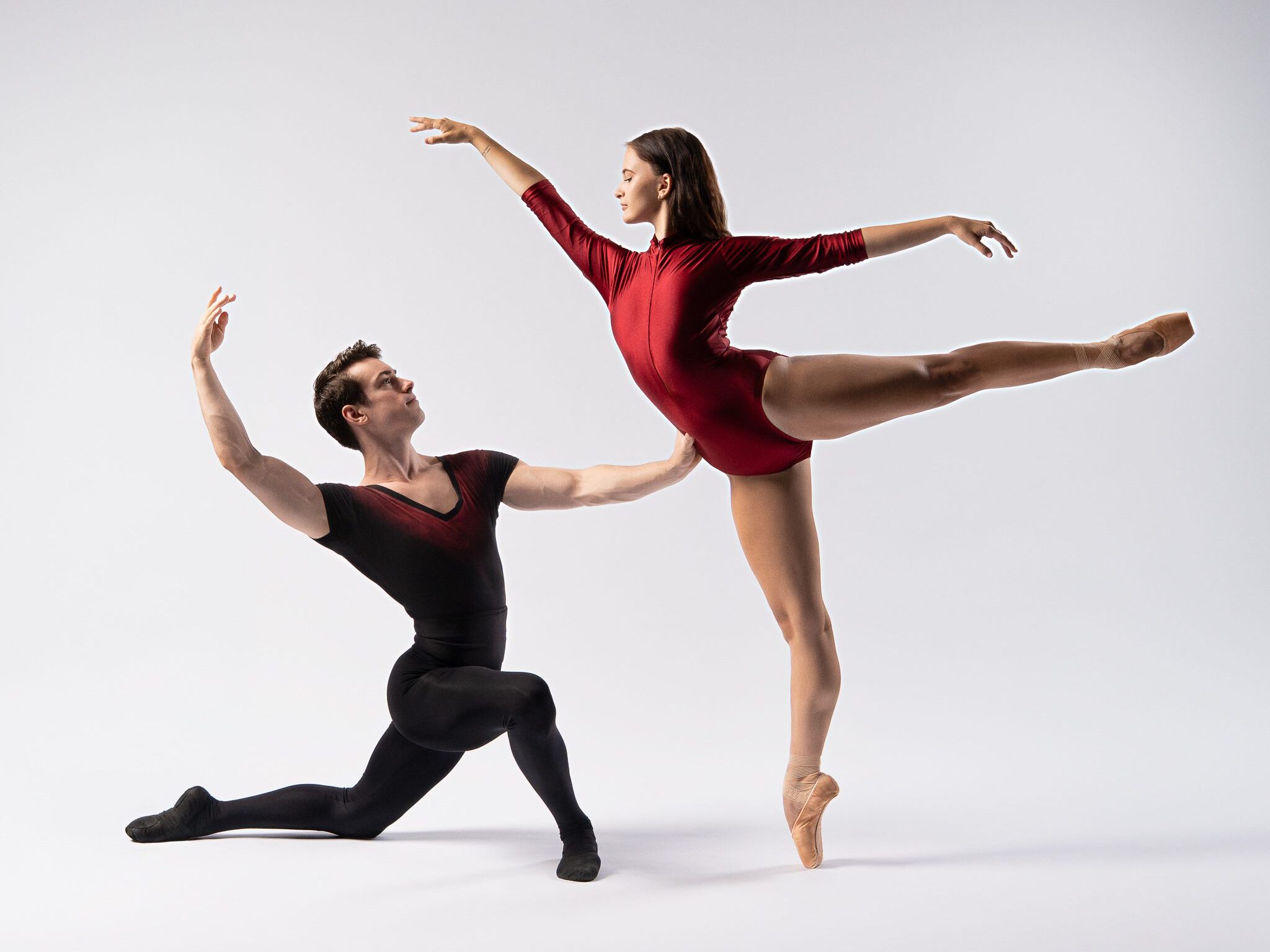 Two young ballet dancers perform a synchronized lift during a dance photography session in San Antonio, with one dancer in arabesque position supported by their partner